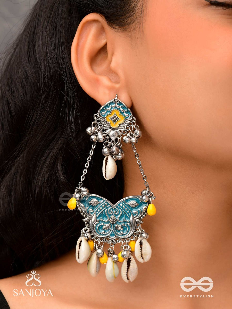 Shankha Pushpa- Conch Blossom-Oxidized Earrings With Pastel-Hued Metalwork, Embellished With Delicate Cowrie Shells, Yellow Beads And Ghungroo