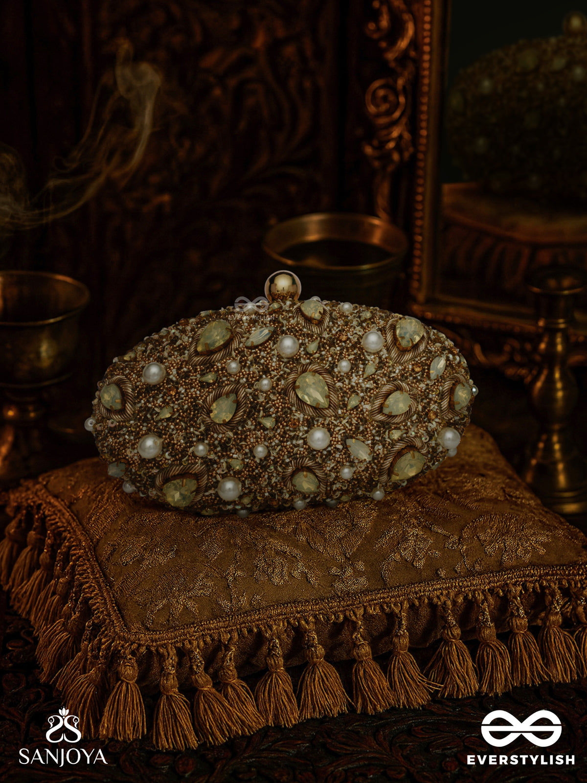 Chandraaya – Polished Oval Golden Bronze Silk Clutch With Intricate Jewel Stone Embellishment And Golden Metal Frame