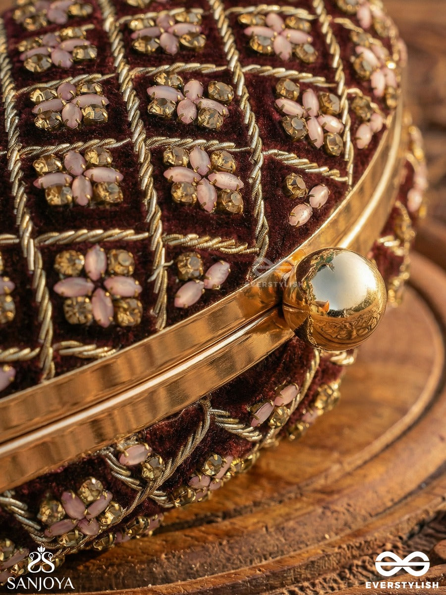 Nazrana – Curved Maroon Shade Textile Clutch With Ornamented Grid Embellishment And Golden Metal Frame