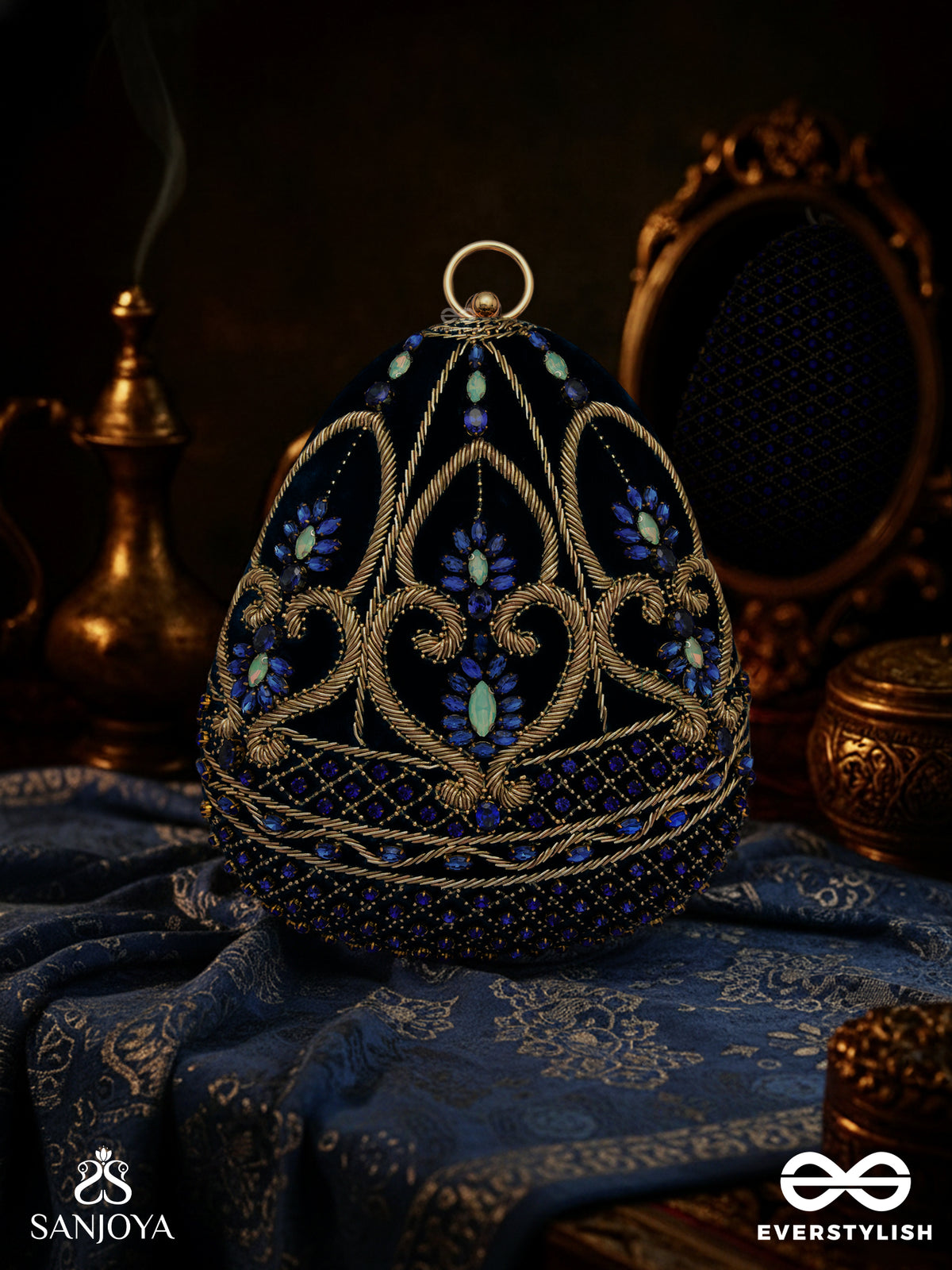 Sitaraa – Polished Oval Royal Blue Velvet Clutch With Stone-Accented Handwork And Golden Metal Frame