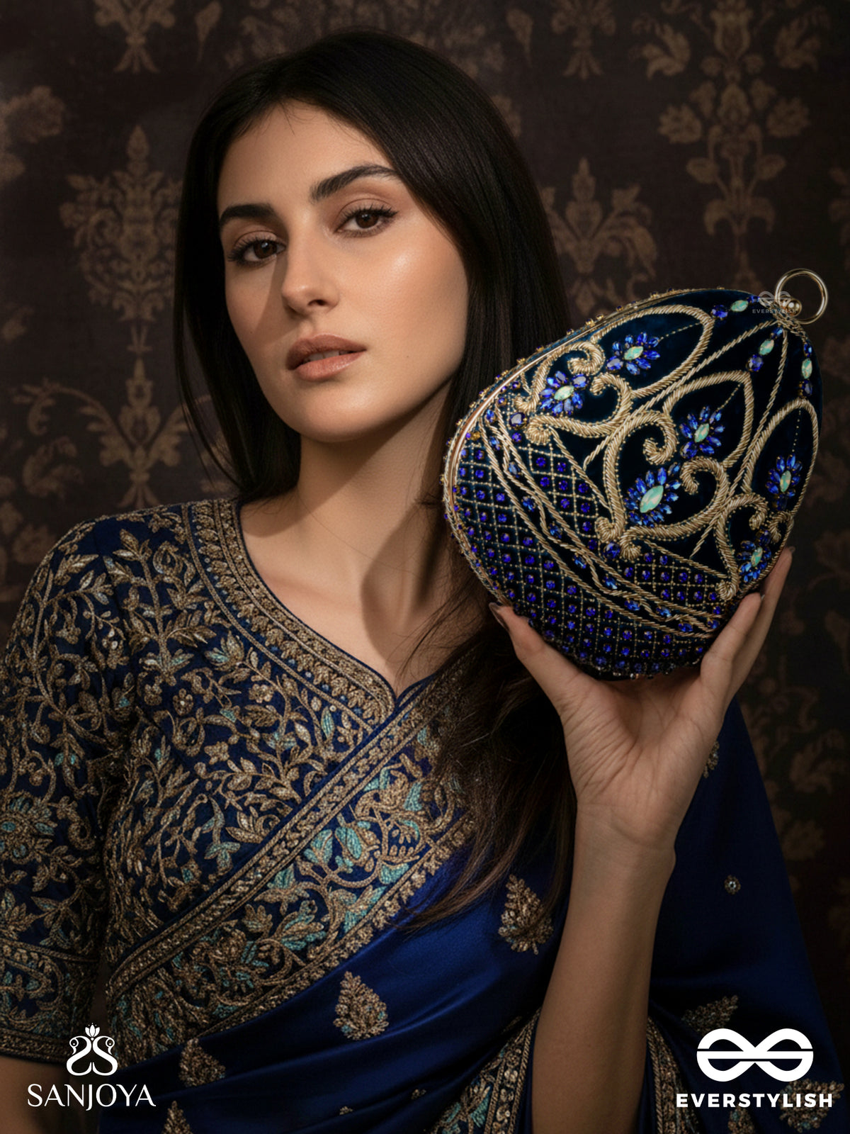 Sitaraa – Polished Oval Royal Blue Velvet Clutch With Stone-Accented Handwork And Golden Metal Frame