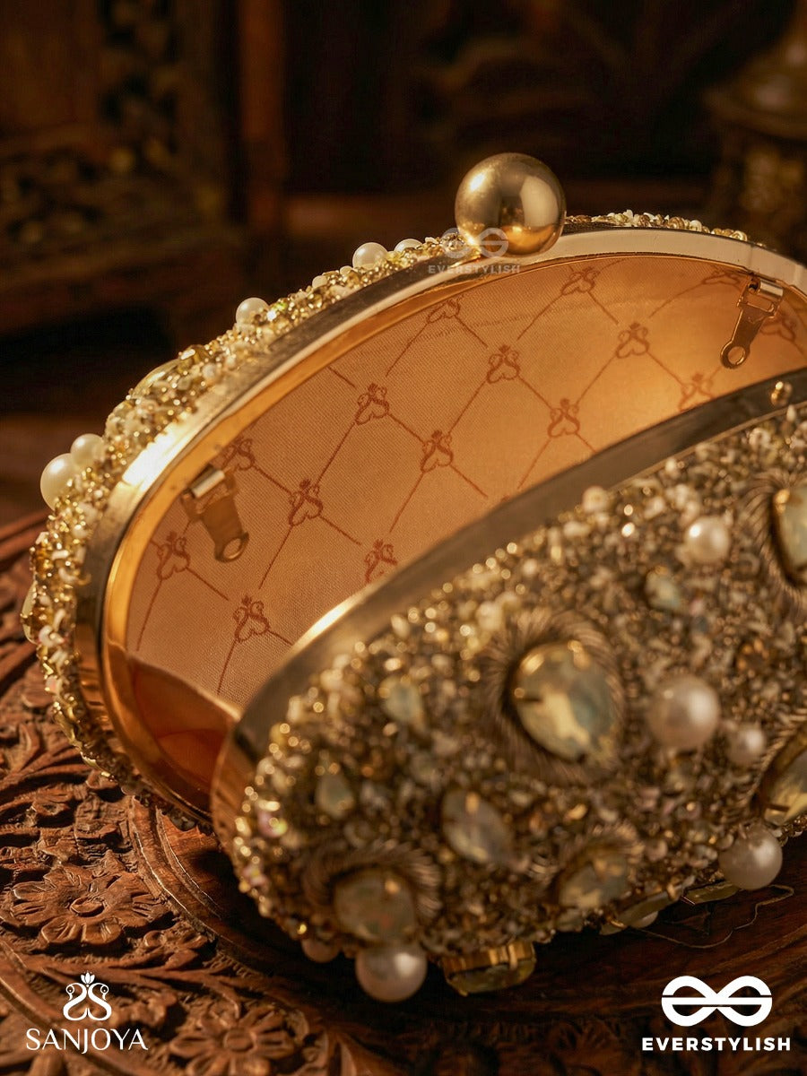 Chandraaya – Polished Oval Golden Bronze Silk Clutch With Intricate Jewel Stone Embellishment And Golden Metal Frame