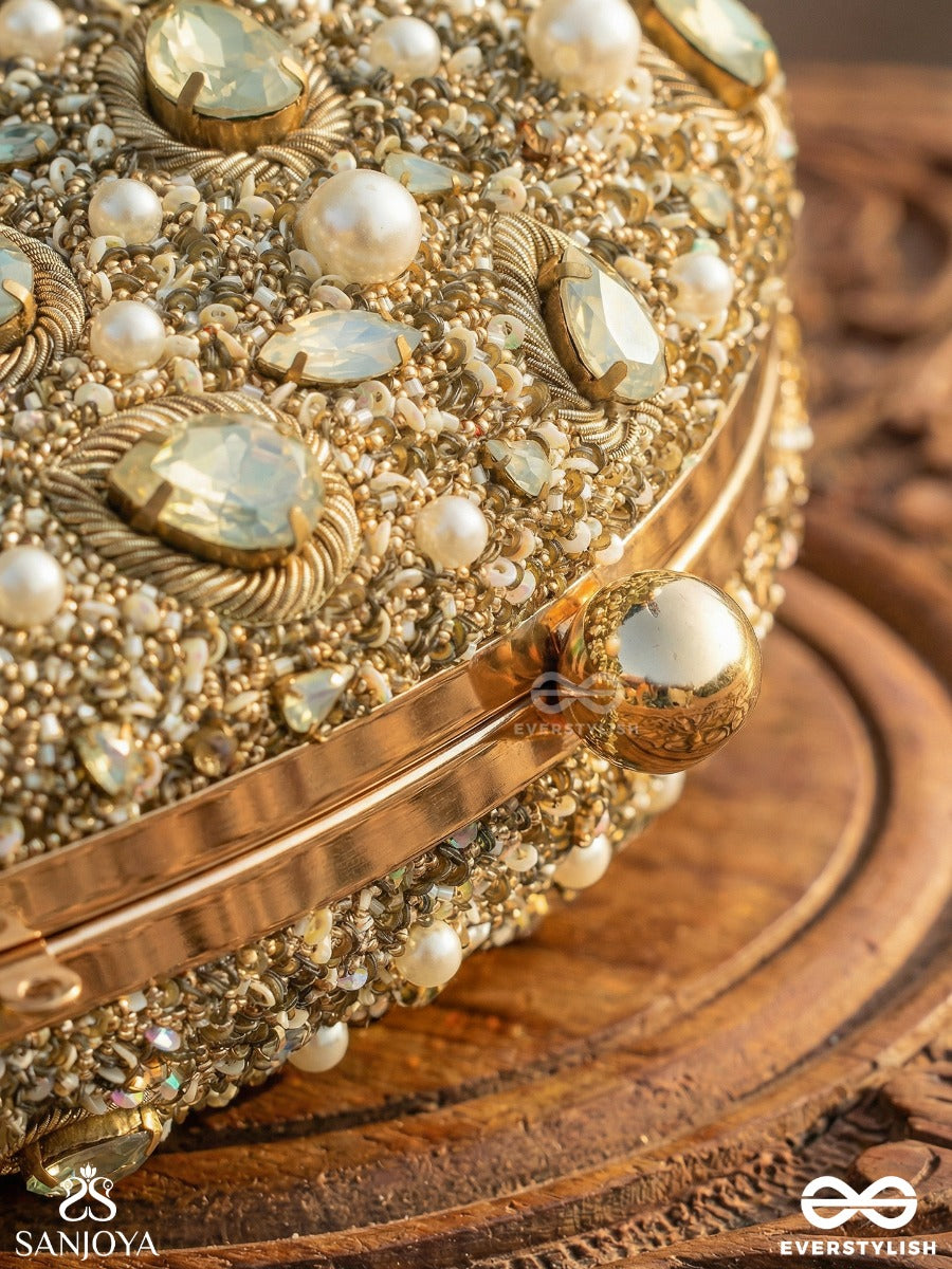 Chandraaya – Polished Oval Golden Bronze Silk Clutch With Intricate Jewel Stone Embellishment And Golden Metal Frame
