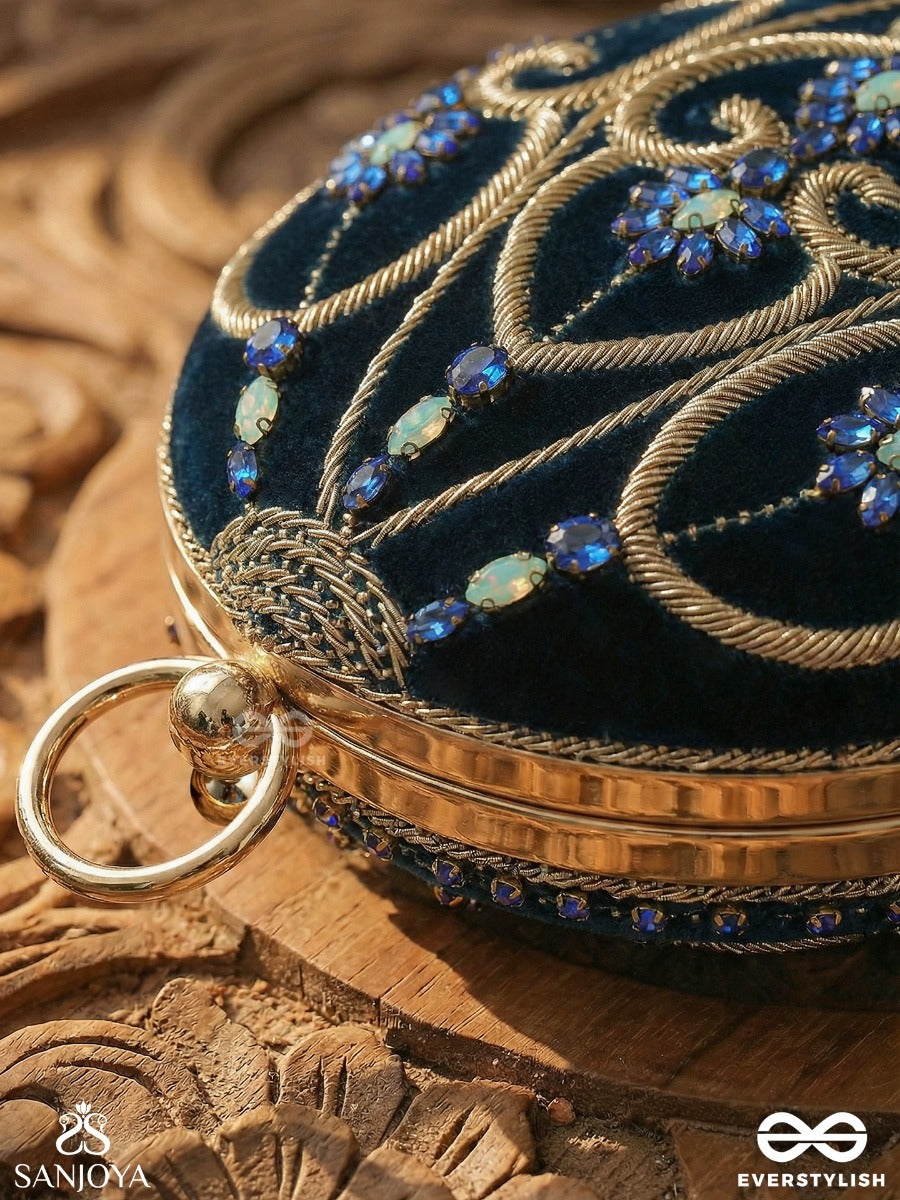 Sitaraa – Polished Oval Royal Blue Velvet Clutch With Stone-Accented Handwork And Golden Metal Frame