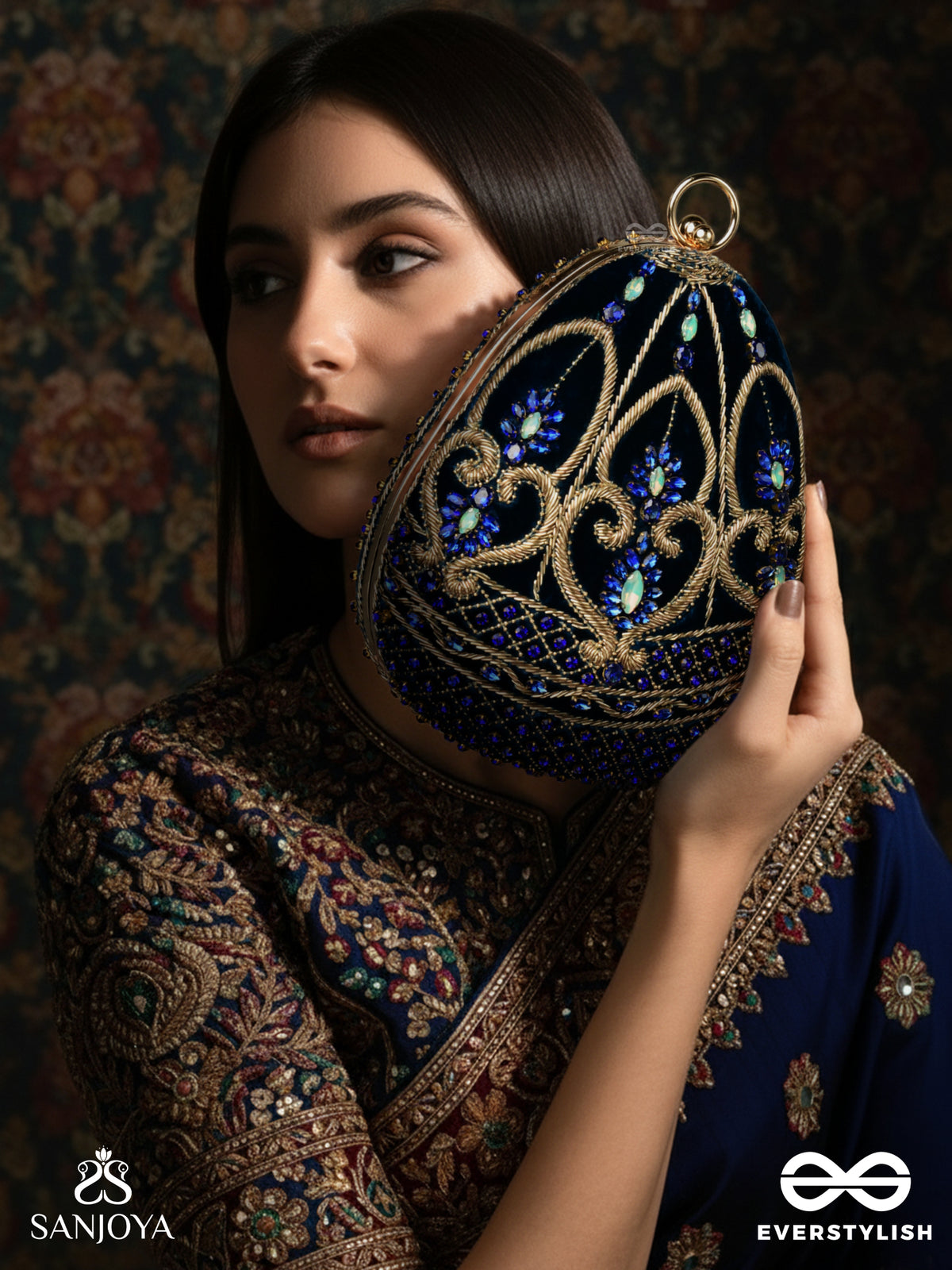 Sitaraa – Polished Oval Royal Blue Velvet Clutch With Stone-Accented Handwork And Golden Metal Frame